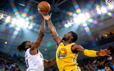 NBA总决赛激烈对抗 - 球员在空中争夺篮球，背景是明亮的球场灯光